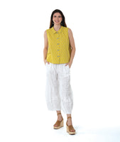 model in a white pant with a checkered yellow and grey print button down sleeveless blouse with a boxy body and a twin button detail