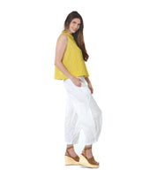 model in a white pant with a checkered yellow and grey print button down sleeveless blouse with a boxy body and a twin button detail