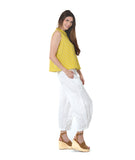 model in a white pant with a checkered yellow and grey print button down sleeveless blouse with a boxy body and a twin button detail
