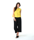 model in a black pant with a checkered yellow and grey print button down sleeveless blouse with a boxy body and a twin button detail