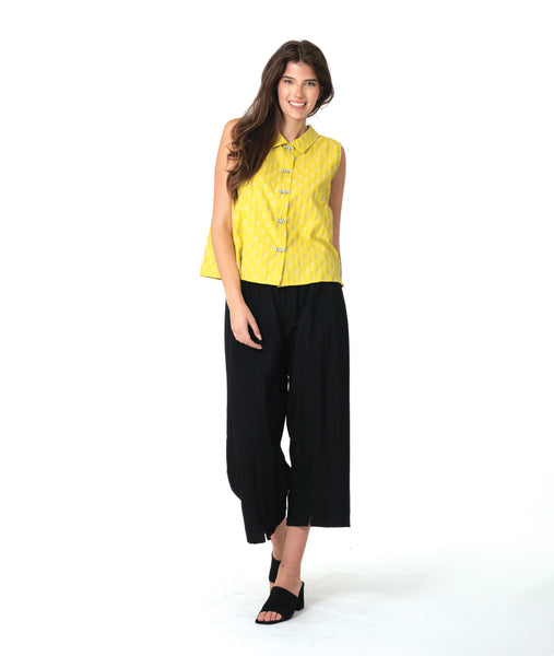 model in a black pant with a checkered yellow and grey print button down sleeveless blouse with a boxy body and a twin button detail