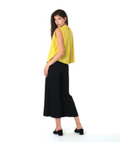 model in a black pant with a checkered yellow and grey print button down sleeveless blouse with a boxy body and a twin button detail