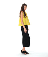 model in a black pant with a checkered yellow and grey print button down sleeveless blouse with a boxy body and a twin button detail
