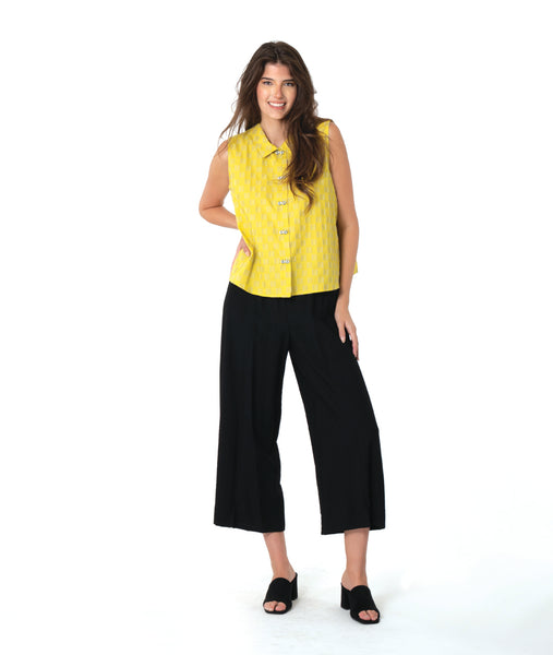 model in a black pant with a checkered yellow and grey print button down sleeveless blouse with a boxy body and a twin button detail