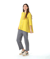 model in a grey pant with a checkered yellow and grey print button down blouse with a full body and dipped hem in the back.