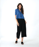 model in a black pant with a checkered blue and grey print button down blouse with short sleeves and a cropped body