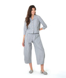 model in a blue and grey pinstripe short, boxy button down with a 3/4 sleeve and flat open collar. worn with a matching barrel leg pant
