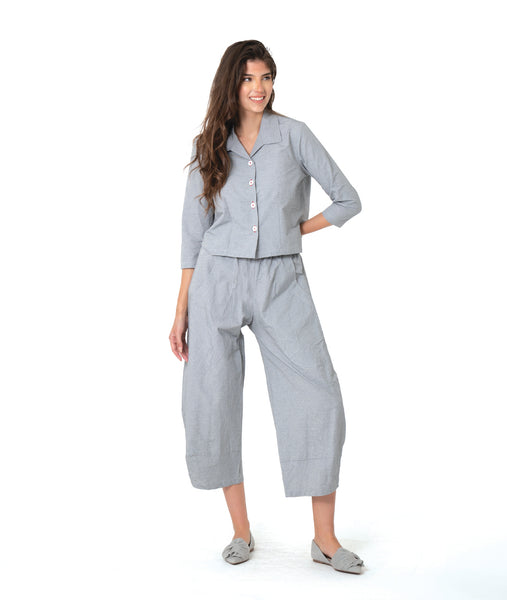 model in a blue and grey pinstripe short, boxy button down with a 3/4 sleeve and flat open collar. worn with a matching barrel leg pant