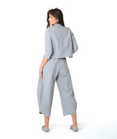 model in a blue and grey pinstripe short, boxy button down with a 3/4 sleeve and flat open collar. worn with a matching barrel leg pant