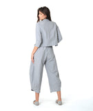 model in a blue and grey pinstripe short, boxy button down with a 3/4 sleeve and flat open collar. worn with a matching barrel leg pant
