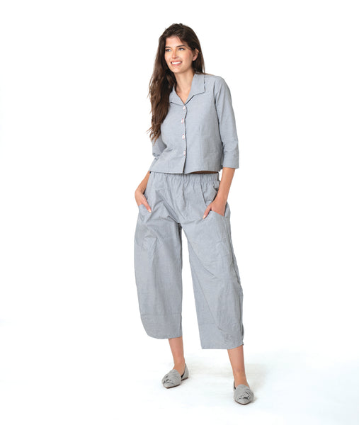 model in a blue and grey pinstripe short, boxy button down with a 3/4 sleeve and flat open collar. worn with a matching barrel leg pant