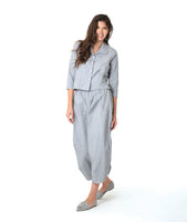 model in a blue and grey pinstripe short, boxy button down with a 3/4 sleeve and flat open collar. worn with a matching barrel leg pant