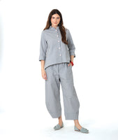 model in a blue and grey pinstripe  button down with a 3/4 sleeve and double collar. worn with a matching barrel leg pant