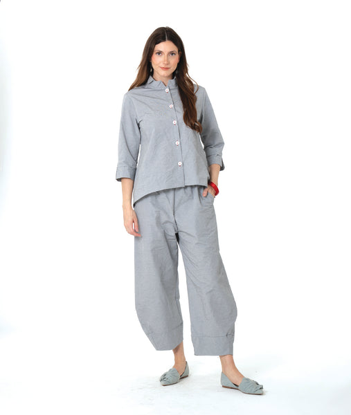 model in a blue and grey pinstripe  button down with a 3/4 sleeve and double collar. worn with a matching barrel leg pant