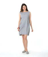 model in a sleeveless pinstripe shift dress with princess sleeves and a squared neckline. pockets are set into the seams and have a red embroidery detail