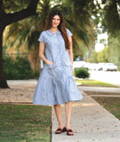 model in a grey and white pinstripe shirtdress with a gathered skirt detailng and hip pockets