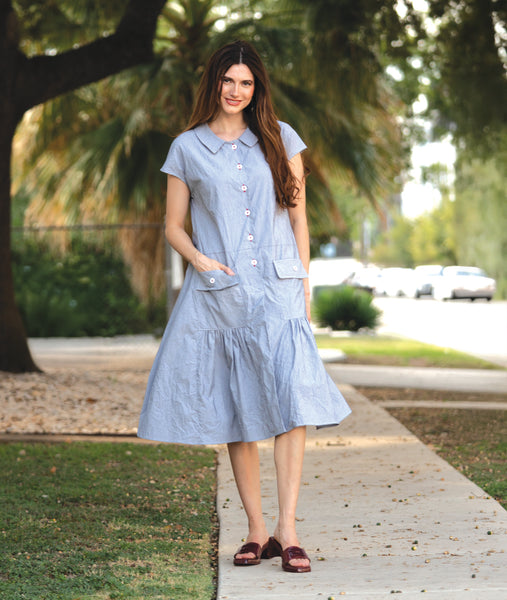 model in a grey and white pinstripe shirtdress with a gathered skirt detailng and hip pockets