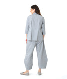 model in a blue and grey pinstripe  button down with a 3/4 sleeve and double collar. worn with a matching barrel leg pant