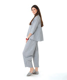 model in a blue and grey pinstripe  button down with a 3/4 sleeve and double collar. worn with a matching barrel leg pant
