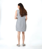 model in a sleeveless pinstripe shift dress with princess sleeves and a squared neckline. pockets are set into the seams and have a red embroidery detail