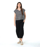 model in a boxy plaid black and white top with a black wide leg pant with a tapered ankle