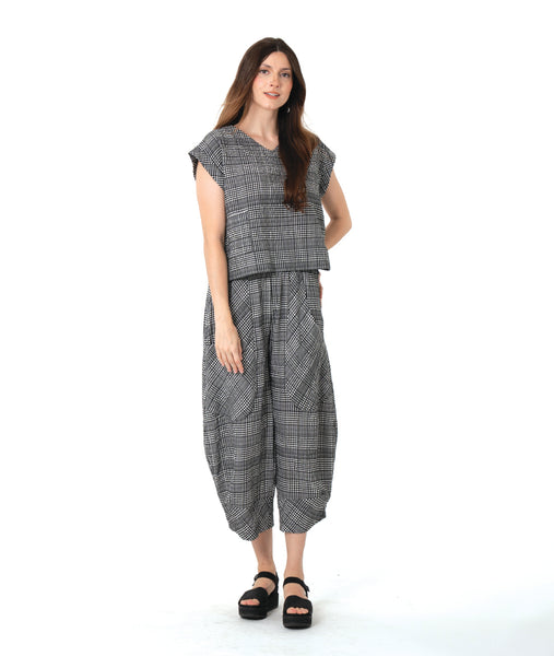 model in a boxy plaid black and white top with a matching wide leg pant with a tapered ankle and oversized exterior pockets