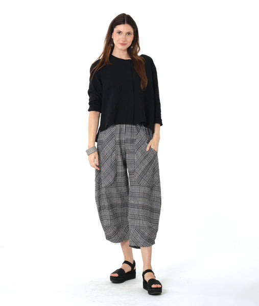 model in a 3/4 sleeve black pullover top with a black and white plaid pant with a wide leg, tapered ankle, and oversized pockets