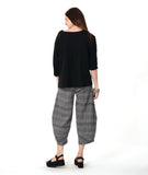 model in a 3/4 sleeve black pullover top with a black and white plaid pant with a wide leg, tapered ankle, and oversized pockets