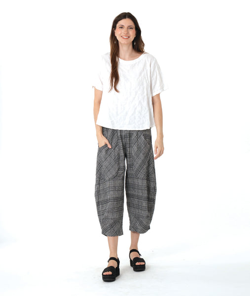 model in a boxy white tee with a wide leg plaid black and white pant
