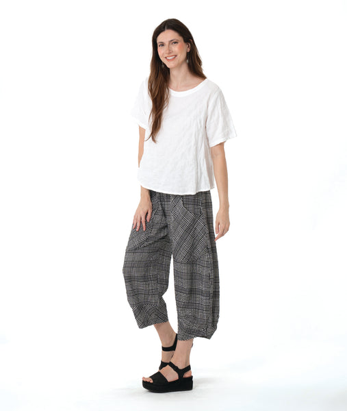 model in a boxy white tee with a wide leg plaid black and white pant