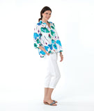 model in a white crop pant with a white pullover top with a vibrant floral print. top has 3/4 sleeves and an open, flat collar