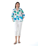 model in a white crop pant with a white pullover top with a vibrant floral print. top has 3/4 sleeves and an open, flat collar