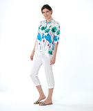 model in a white crop pant with a white button down blouse with a vibrant floral print. top has 3/4 sleeves and a mandarin style collar