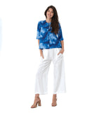 model in a wide leg white pant, worn with a multi tonal blue print button down blouse