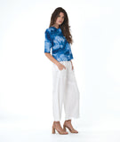 model in a wide leg white pant, worn with a multi tonal blue print button down blouse