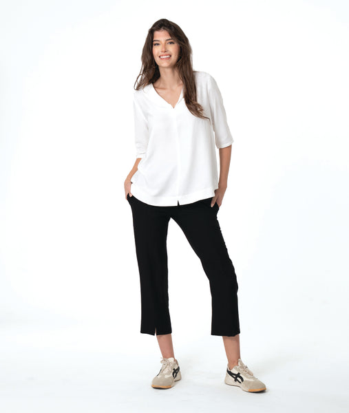 model in a slim black pant, worn with a white pullover top with a wide, flat collar