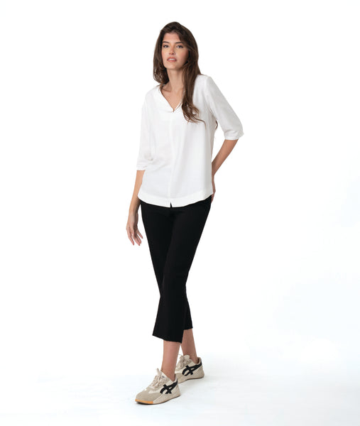 model in a slim black pant, worn with a white pullover top with a wide, flat collar