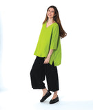 model in a slim black pant, worn with a lime color pullover blouse with a low back hem and a vneck