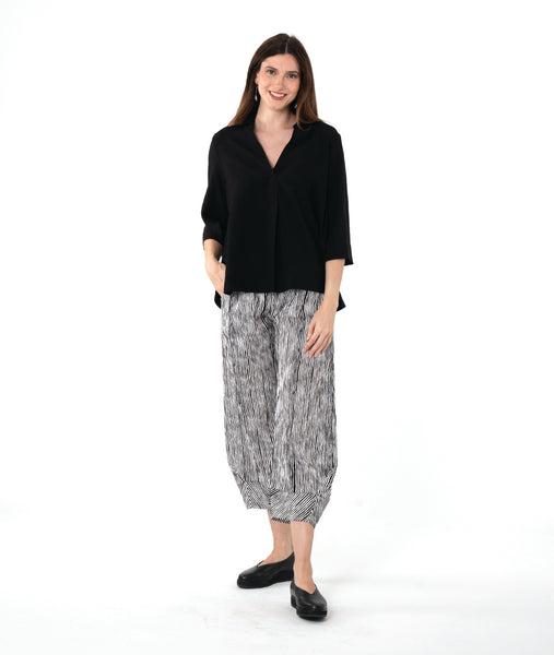 model in a black and white stripe pant, worn with a black pullover top with an open, flat collar