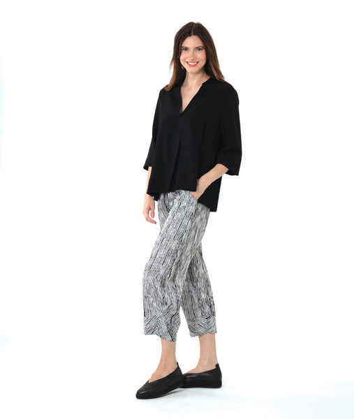 model in a black and white stripe pant, worn with a black pullover top with an open, flat collar