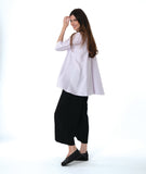 model in a wide leg black pant worn with a soft pink button down with a full body and extra large rounded pockets