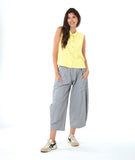 model in a grey and white pinstripe pant, worn with a soft yellow sleeveless button down blouse