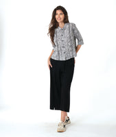 model in a wide leg black pant with a black and white striped button down blouse with 3/4 sleeves