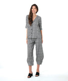 model in a barrel leg black and white striped pant, with a matching button down blouse with a flat, open collar and 3/4 sleeves