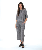 model in a black and white striped button down blouse with 3/4 sleeves, worn with a matching wide leg cargo pant with asymmetrical pockets