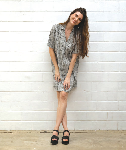 model in a black and white striped dress with short sleeves, knee length and an open, flat collar