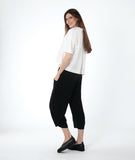 model in a wide leg black pant with a boxy white button down blouse with an open, flat collar and a twin button detail