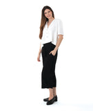 model in a wide leg black pant with a boxy white button down blouse with an open, flat collar and a twin button detail