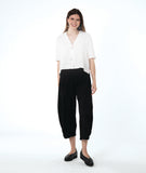 model in a wide leg black pant with a boxy white button down blouse with an open, flat collar and a twin button detail