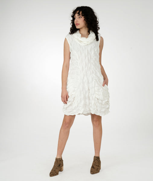 model in a white textured sleeveless tunic with an oversized cowl neck, princess seams and pockets set into the side seams